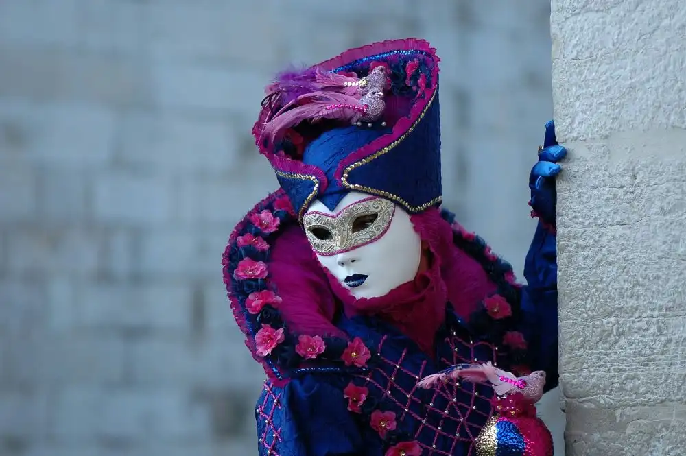 Incantevole maschera del Carnevale di Venezia, la baschera bianca su un vestito blue e viola